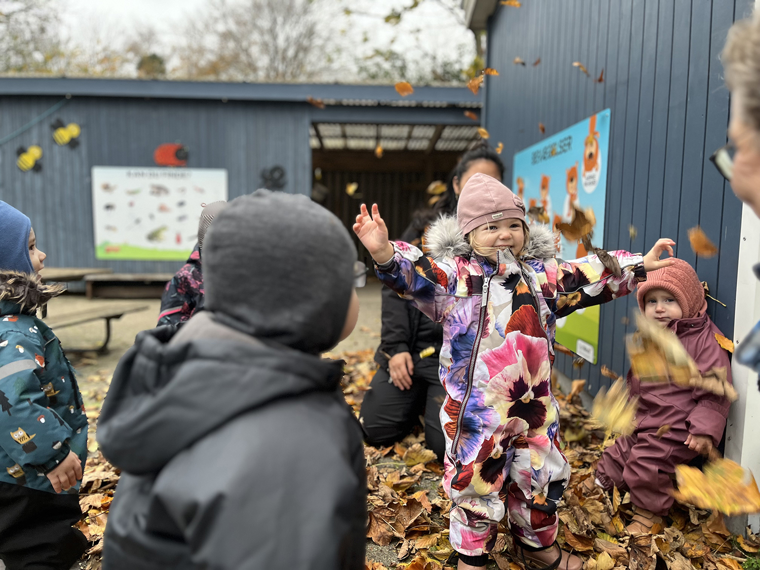Glade børnehavebørn der lege med efterårsblade i gyldne farver
