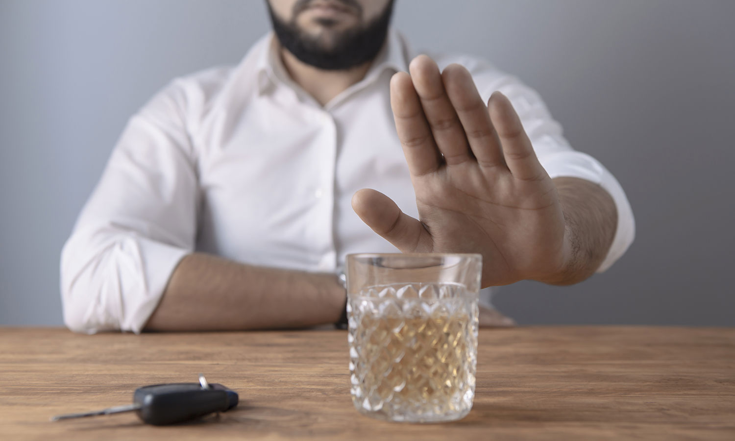 Mand der signalerer med hånden at han afviser et glas whisky