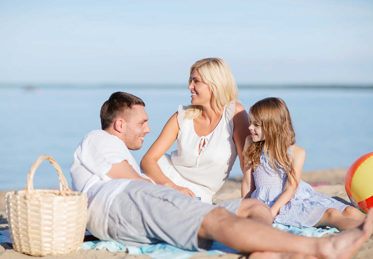 Far, mor og datter der ligger på stranden