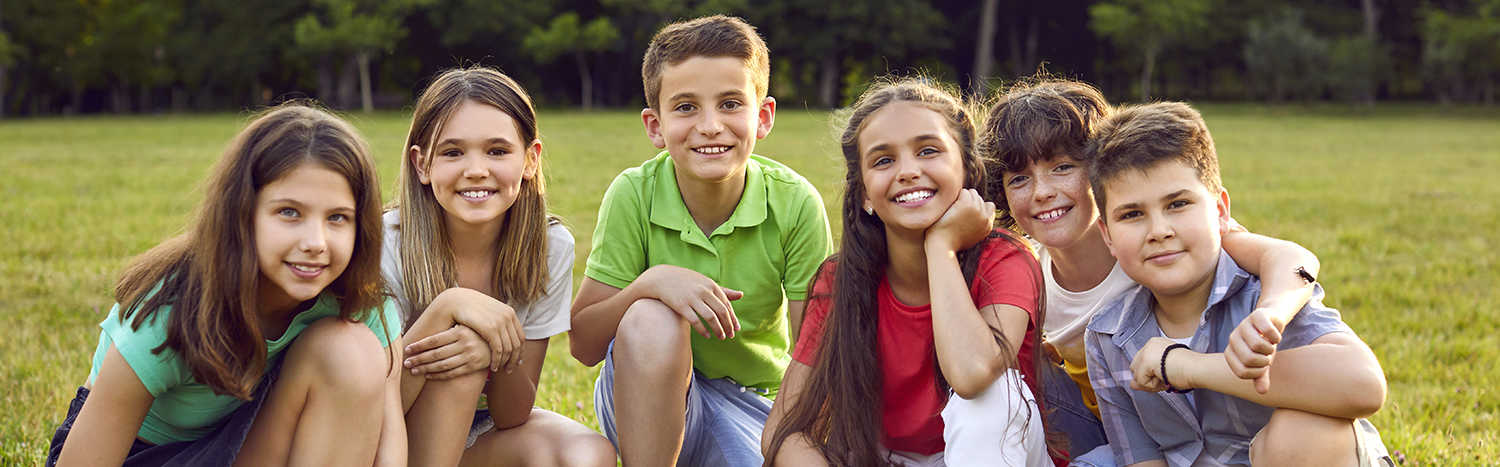 Seks børn sidder på græsplæne